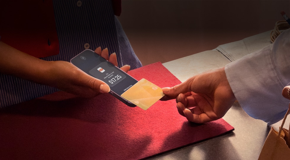 A hand taps a credit card to an iPhone to complete a payment