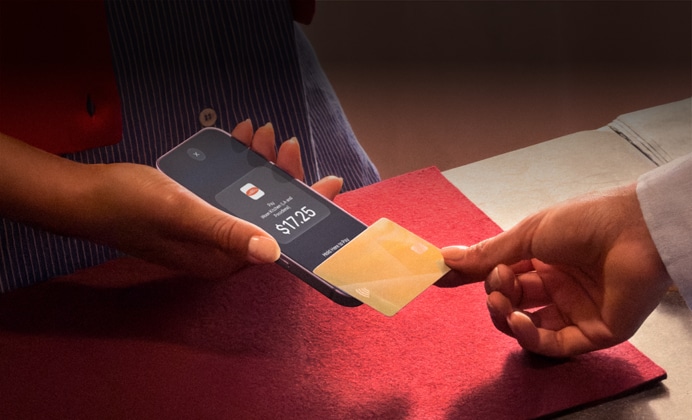 A hand taps a credit card to an iPhone to complete a payment