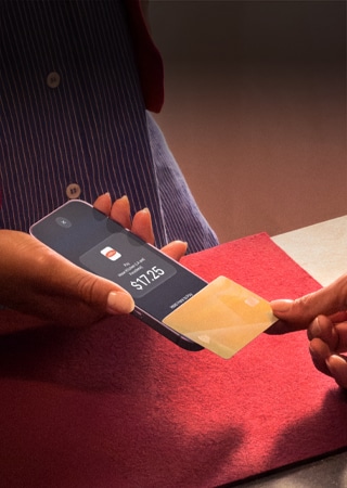 A hand taps a credit card to an iPhone to complete a payment