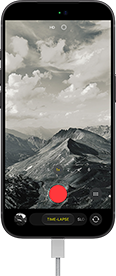 iPhone 18 Pro, front exterior, displaying a mountainous landscape, with the camera mode overlay in Time-Lapse mode, with power cable attached to charging port