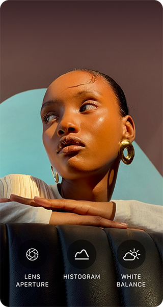 A person with their head turned to the side, bright light shines on them from opposite direction, their hands overlapped on a flat surface in front of them at shoulder height, three photo controls: Lens Aperture, Histogram, and White Balance