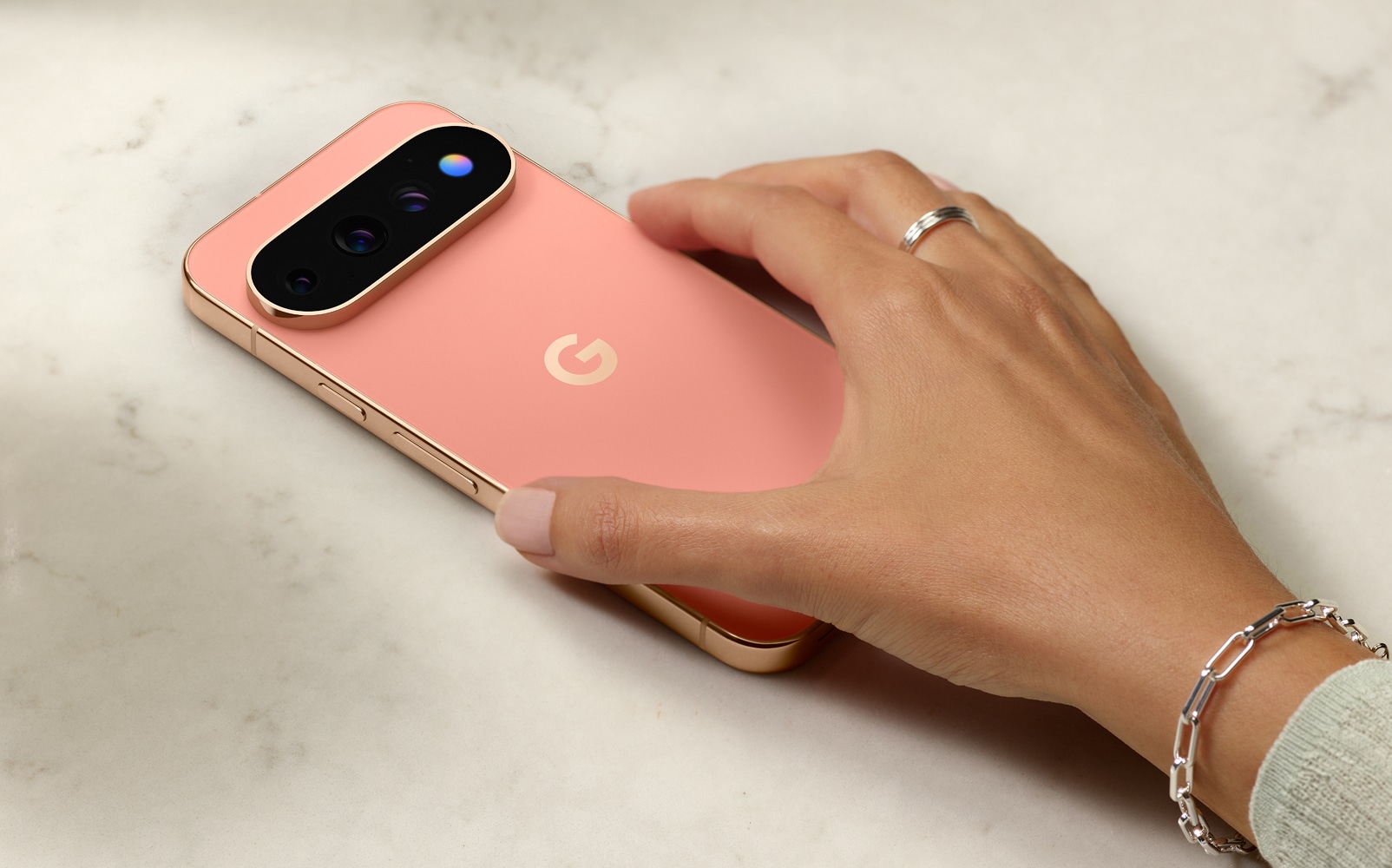 A hand picking up a Pixel 11 Pro face down on a surface, with HiLight glowing