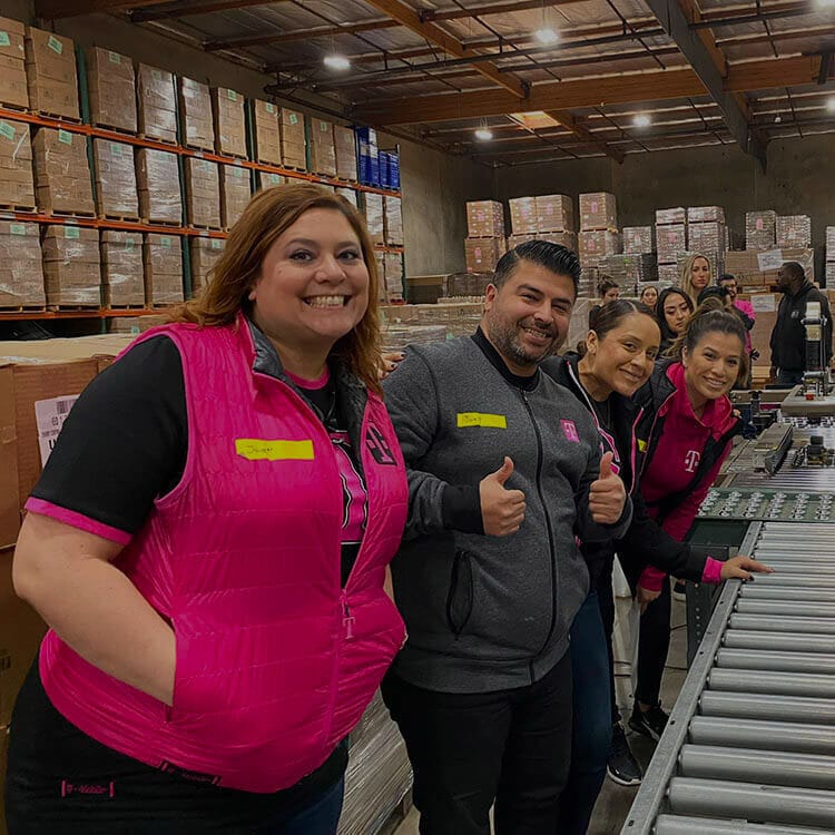 Empleados de T-Mobile sonriendo en un depósito.