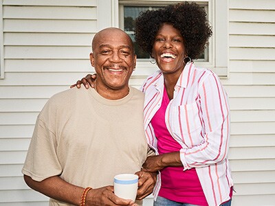 Man and woman smiling in front of a home