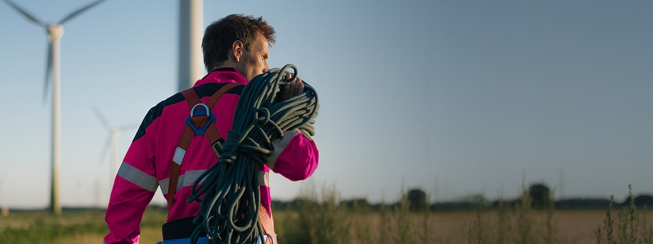 Un hombre a punto de hacer mantenimiento en molinos de viento.