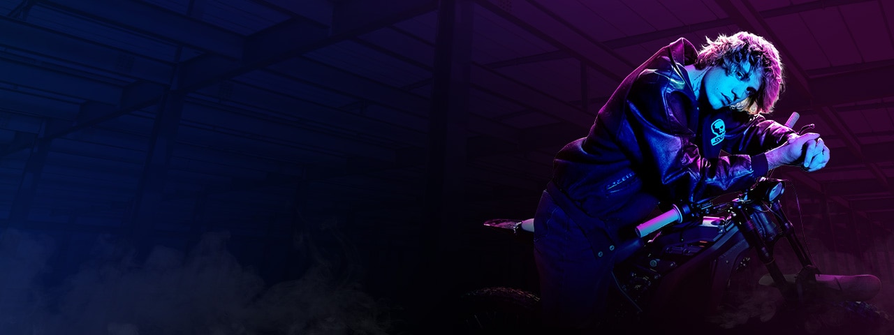 Justin Bieber sits on a motorcycle under blue and purple lighting.
